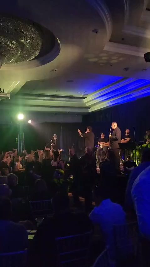 Live Greek music concert in an elegant California ballroom, singer performing for a packed crowd