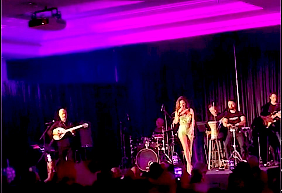Greek singer and live band with bouzouki on a purple-lit stage at a Greek event in California